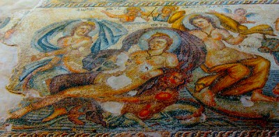 Thetis und Peleus. Mosaik im Haus des Aion zu Paphos, Zypern. Die Gesamtansicht dieses im Jahre 1983 entdeckten Mosaiks zeigt mittig die Göttin Thetis, welche von Peleus getragen wird. Peleus selbst auf einem Drachen ruhend, trägt keinen Namen. Rechts von Thetis und Peleus finden sich außerhalb dieser Detailansicht die Göttin Galatea, sowie der noch junge, auf einem Stier reitende Pontos und Bythos, der Gott der Tiefsee, dargestellt. Links davon Doris, die Mutter der Thetis. Oberhalb sind zudem Zeus und Athene genannt. Quelle der Abbildung : Chypre Paphos : La maison d' Aion, les mosaiques, Septembre 2019. Foto : Mit freundlicher Genehmigung von : Marie Hélène Valliez 2004. Lizenz : CC-BY-3.0.